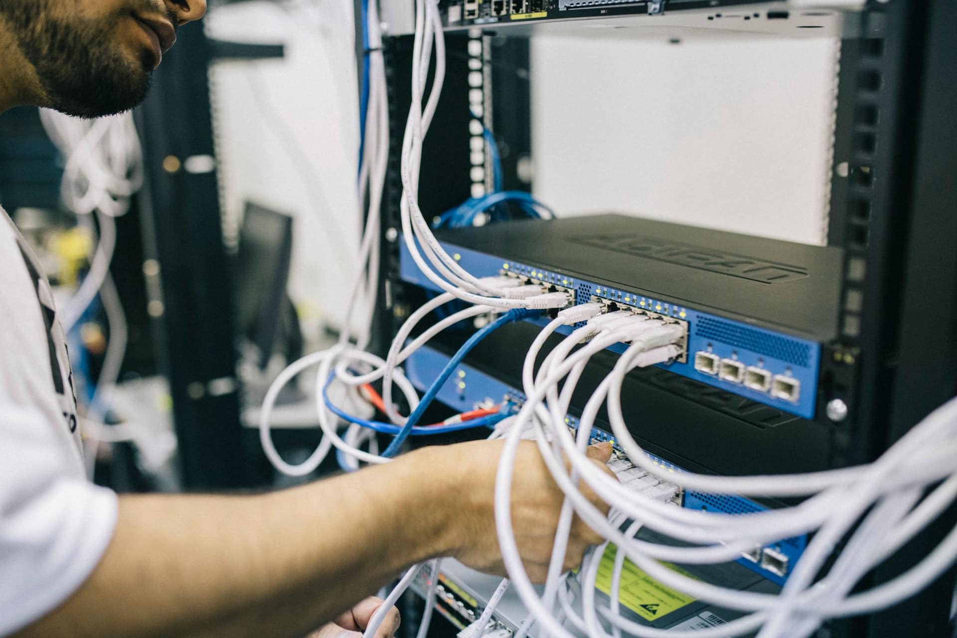 A technician patching network cables into a rack mounted switch